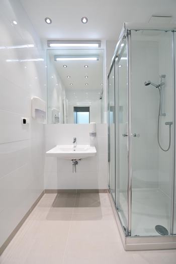 Minimalistická biela kúpeľňa na Avelane clinic so sprchovacím kútom a umývadlom