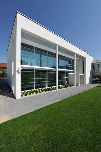 Exteriér kliniky Hlavný vstup do Avelane clinic s presklenou fasádou a zeleným trávnikom